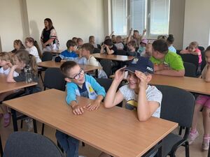 Dzieci, jedno dziecko w czapce policyjnej.