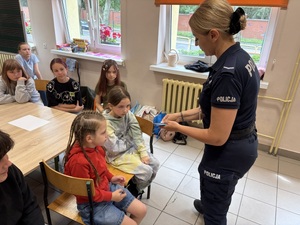 Policjantka rozdaje ulotki dzieciom