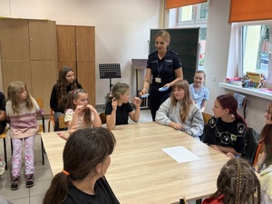 Policjantka rozdaje ulotki dzieciom