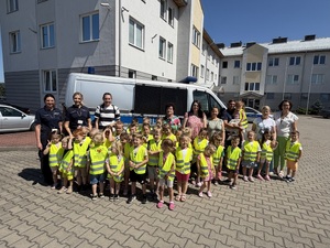 Zdjęcie grupowe dzieci z policjantami na tle radiowozu
