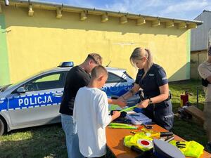 Policjantka przy stoisku profilaktycznym rozmawia z chłopcami