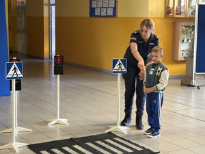 Policjantka pokazuje dziecku jak należy przechodzić przez przejście