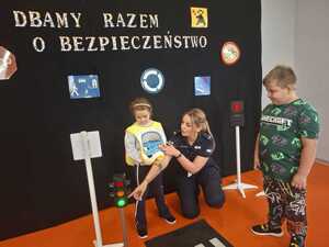 Dzieci ćwiczą z policjantką przechodzenie przez jezdnię