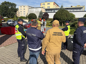 Policjanci i strażacy stoją i planują wspólne działania