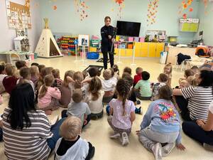 Policjantka stoi i rozmawia z przedszkolakami