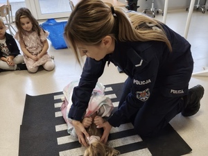 Policjantka ćwiczy z dziećmi jak zachować się podczas kontaktu z agresywnym zwierzęciem